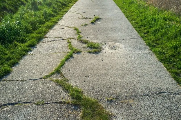 Cracked and uneven concrete driveway with visible surface damage at a residential property