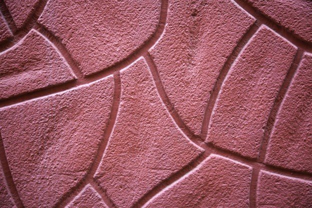 Decorative stamped concrete surface being finished with textured pattern during installation